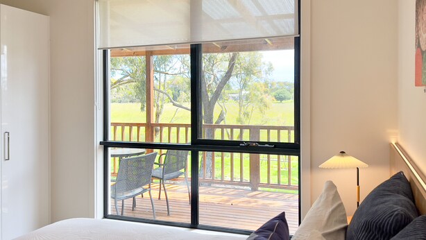 Un dormitorio con un ventanal grande, una cama y vistas a una terraza y zona exterior.