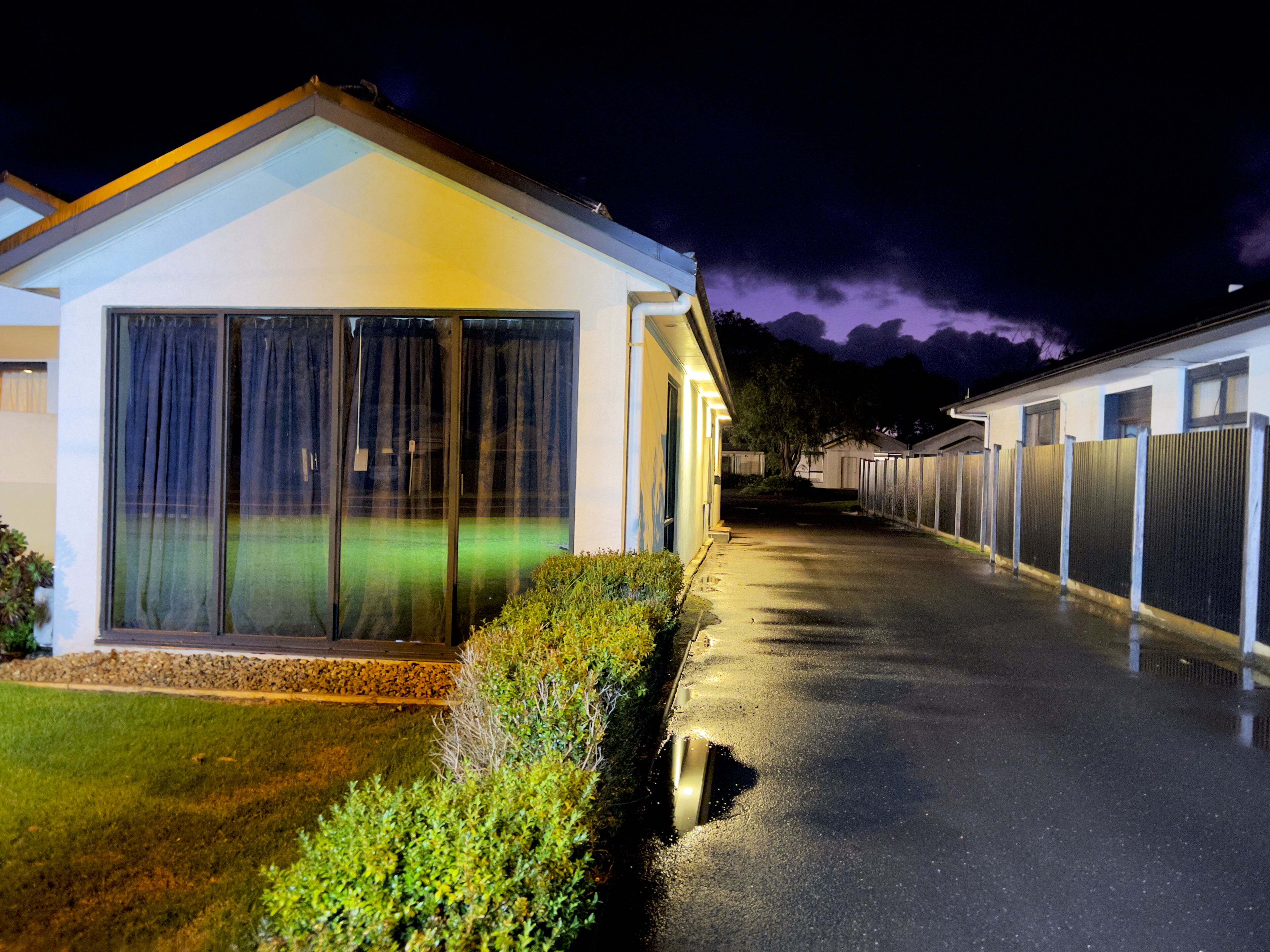 A row of modern, single-story mobile homes with large windows and a well-lit driveway.