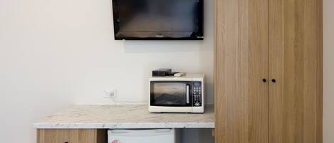 A kitchenette with a microwave, a small refrigerator, and a wall-mounted air conditioner.