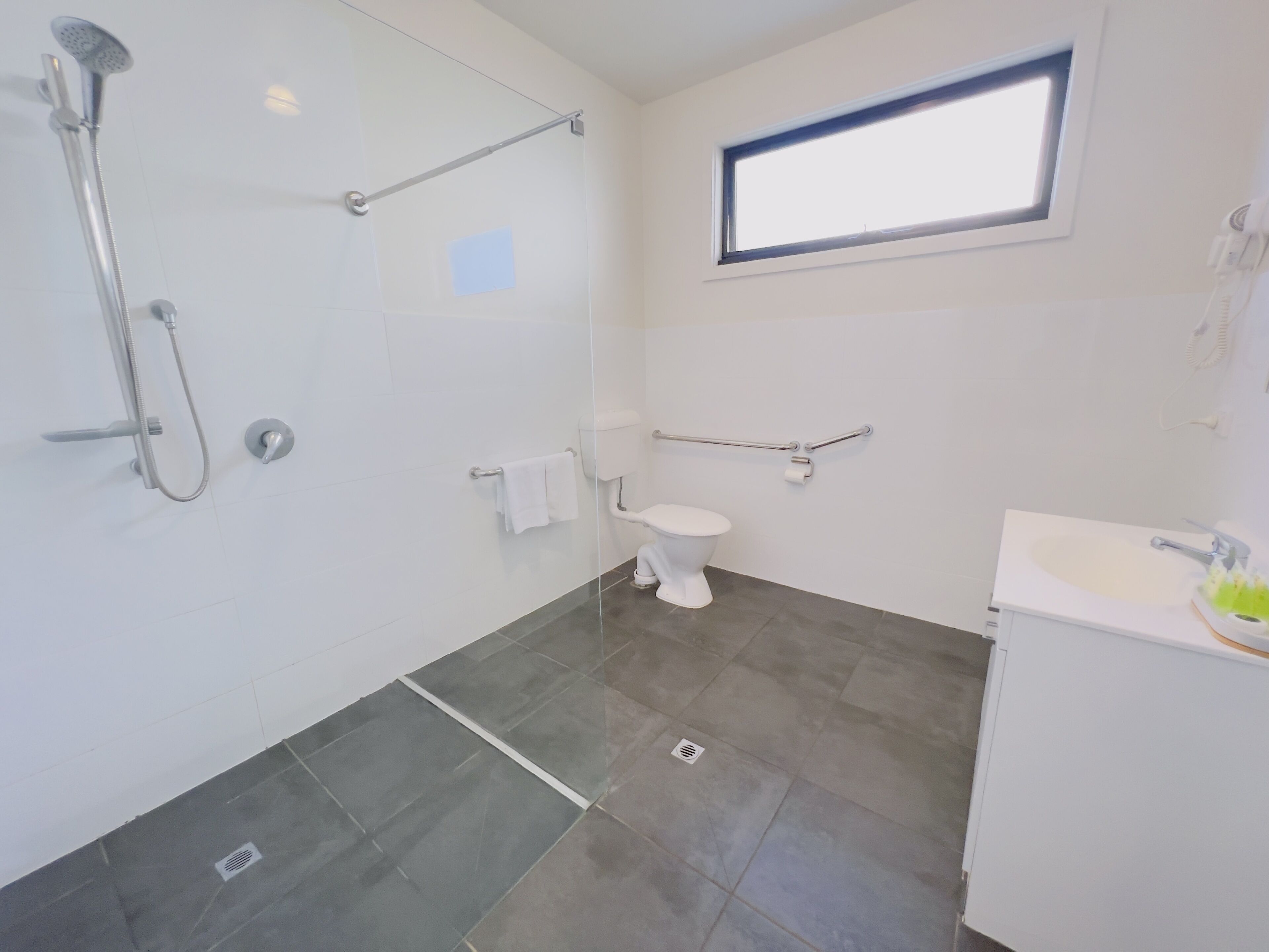 Un baño moderno con cabina de ducha de vidrio, inodoro y lavamanos.