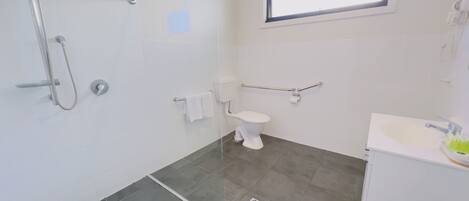 Un baño moderno con cabina de ducha de vidrio, inodoro y lavamanos.