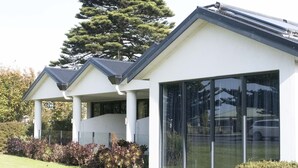Un edificio moderno con fachada blanca, ventanas grandes y un área exterior cubierta con columnas.