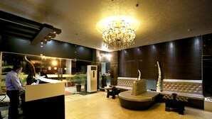 A lobby with a reception desk, seating area, and a chandelier. - Hotel Oyster (Chandigarh)