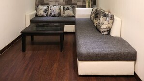 A modern living room with a sectional sofa, a coffee table, and a decorative wall. - Hotel Oyster (Chandigarh)