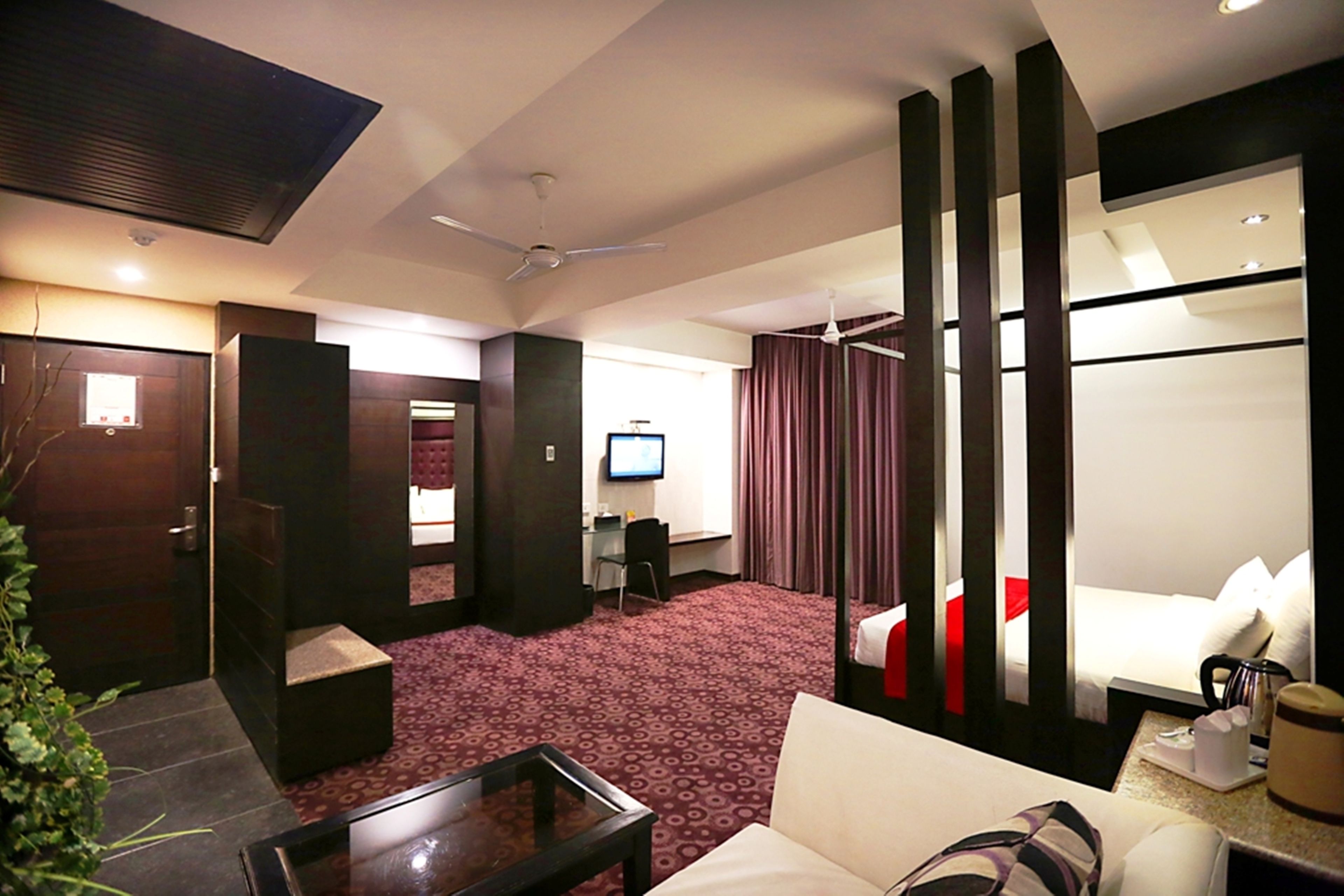 A hotel room with a bed, a desk, a television, and a seating area with a table and chairs.