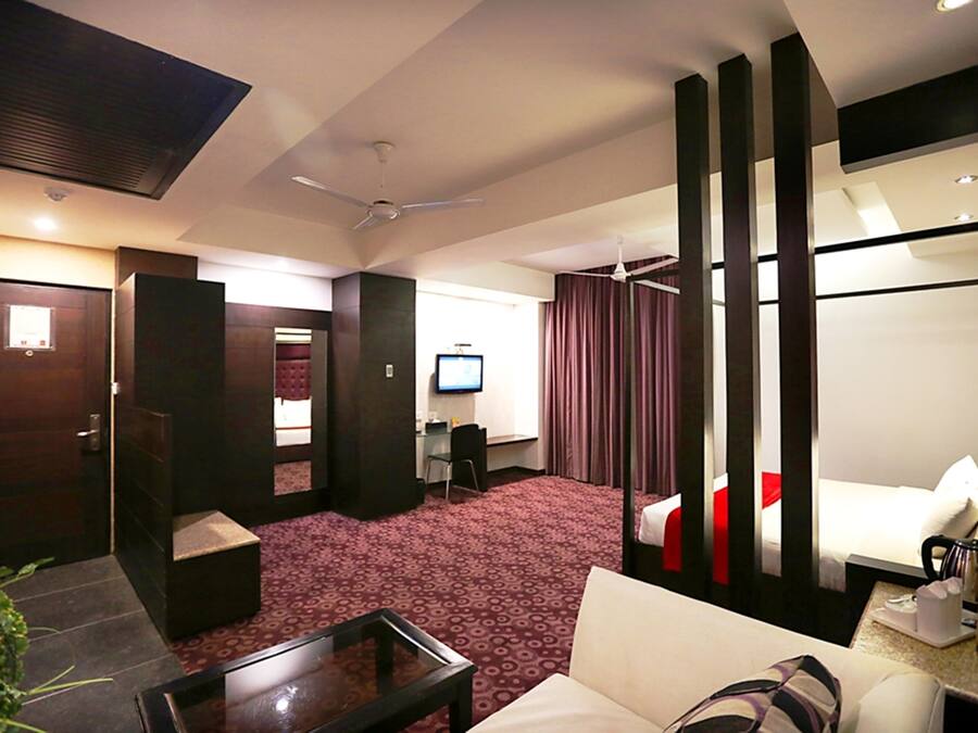 A hotel room with a bed, a desk, a television, and a seating area with a table and chairs.