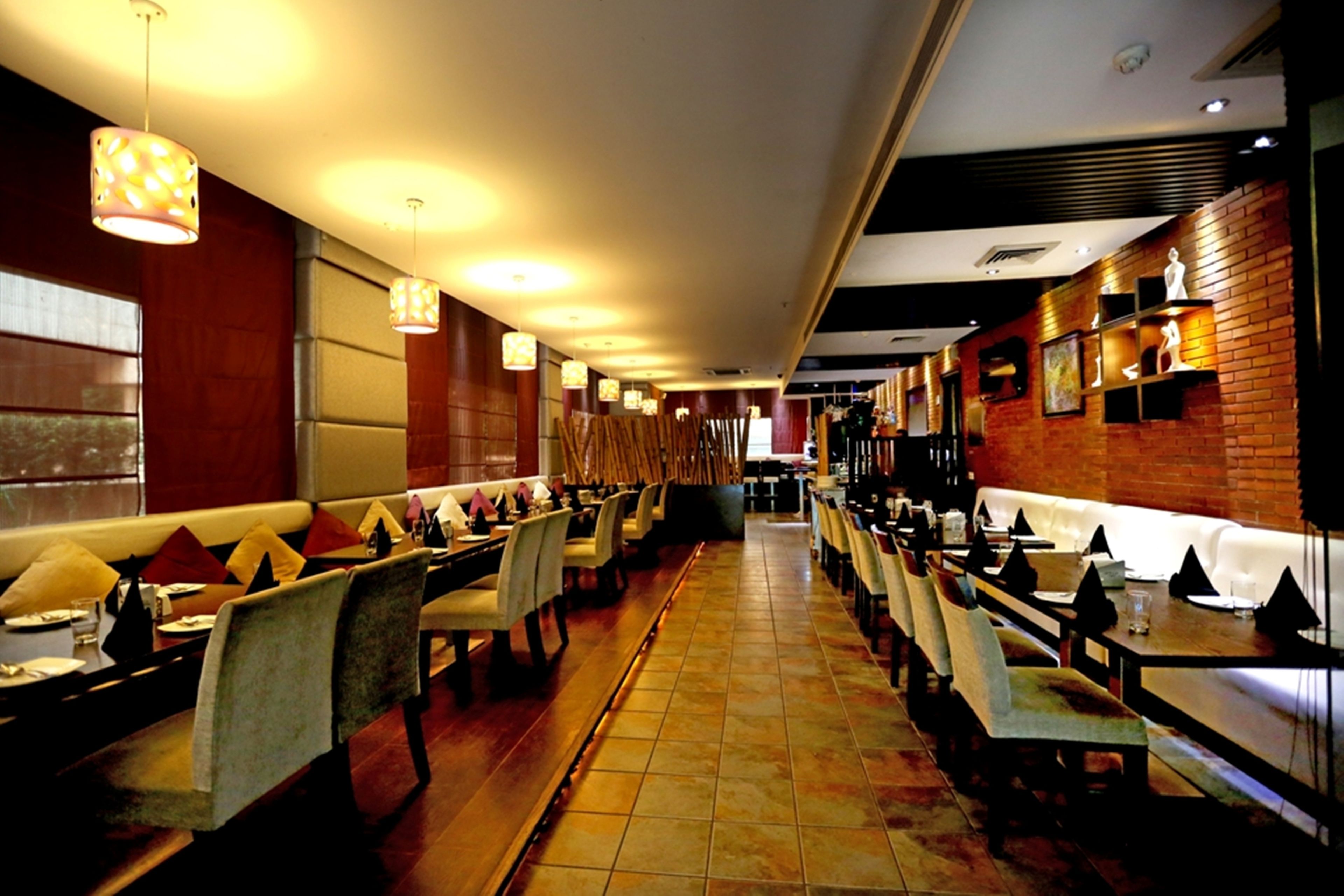 Un restaurant doté de longues tables communes, de banquettes et de luminaires suspendus.