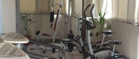 A gym with exercise equipment, a small table, and a potted plant.