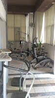 Un gimnasio con equipamiento de ejercicio, una mesa pequeña y una planta en maceta.