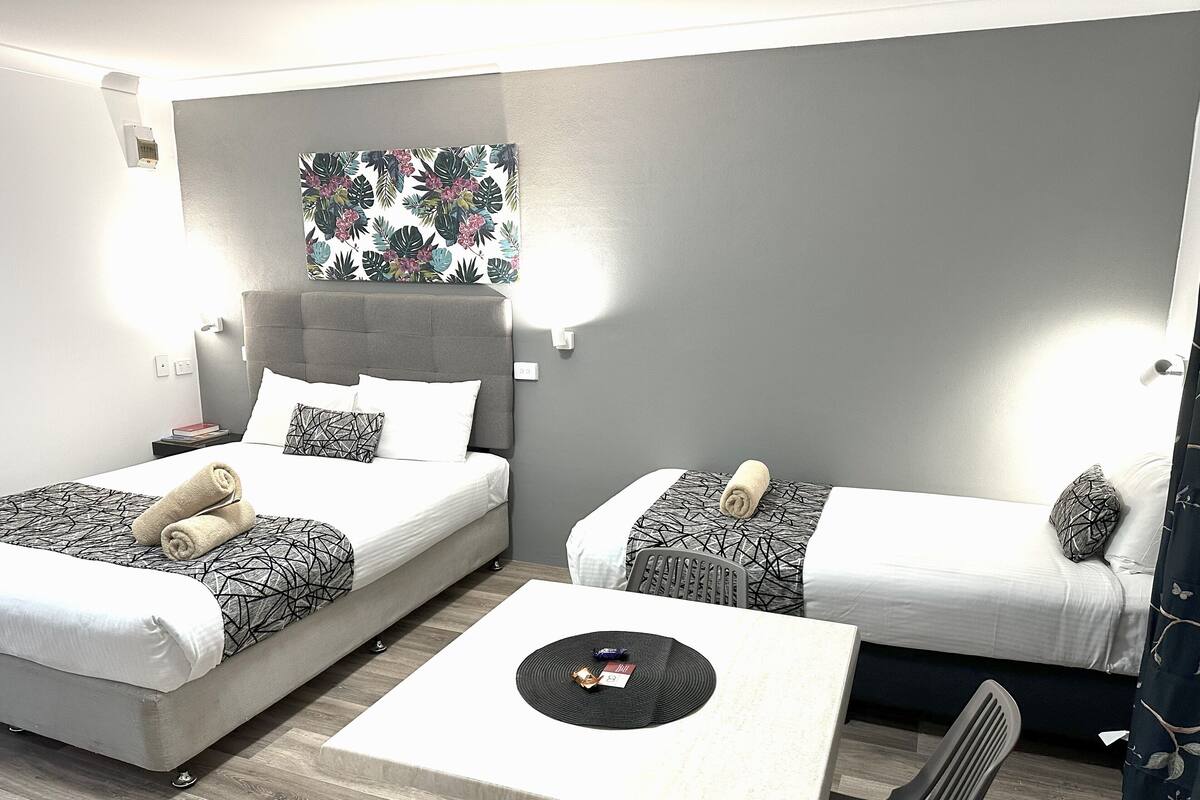 Ein Hotelzimmer mit zwei Betten, einem kleinen Tisch und einem Sessel.