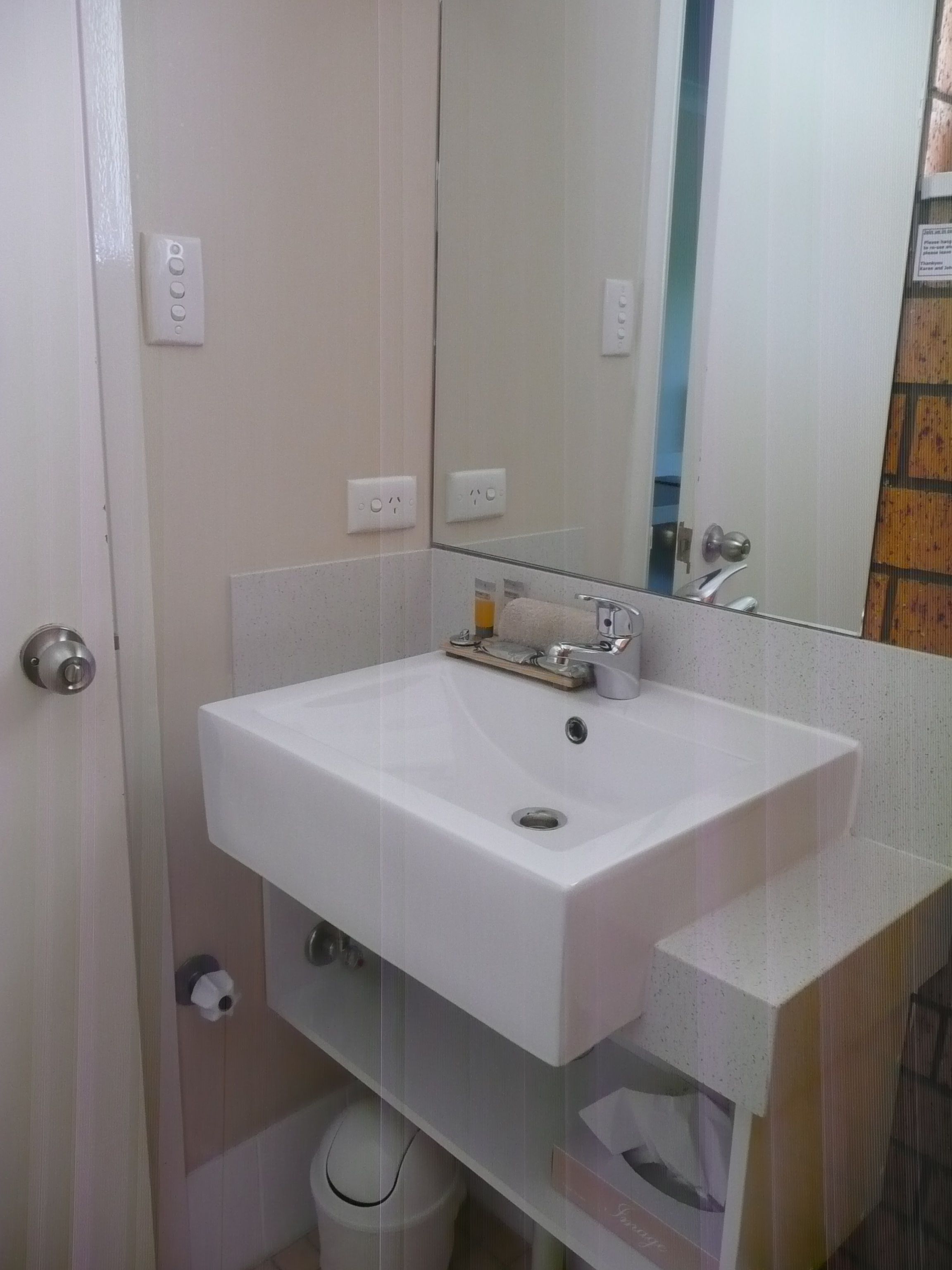 Un baño con un lavamanos blanco, un espejo y un inodoro.