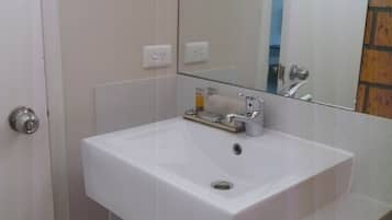Un baño con un lavamanos blanco, un espejo y un inodoro.
