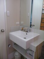Un baño con un lavamanos blanco, un espejo y un inodoro.