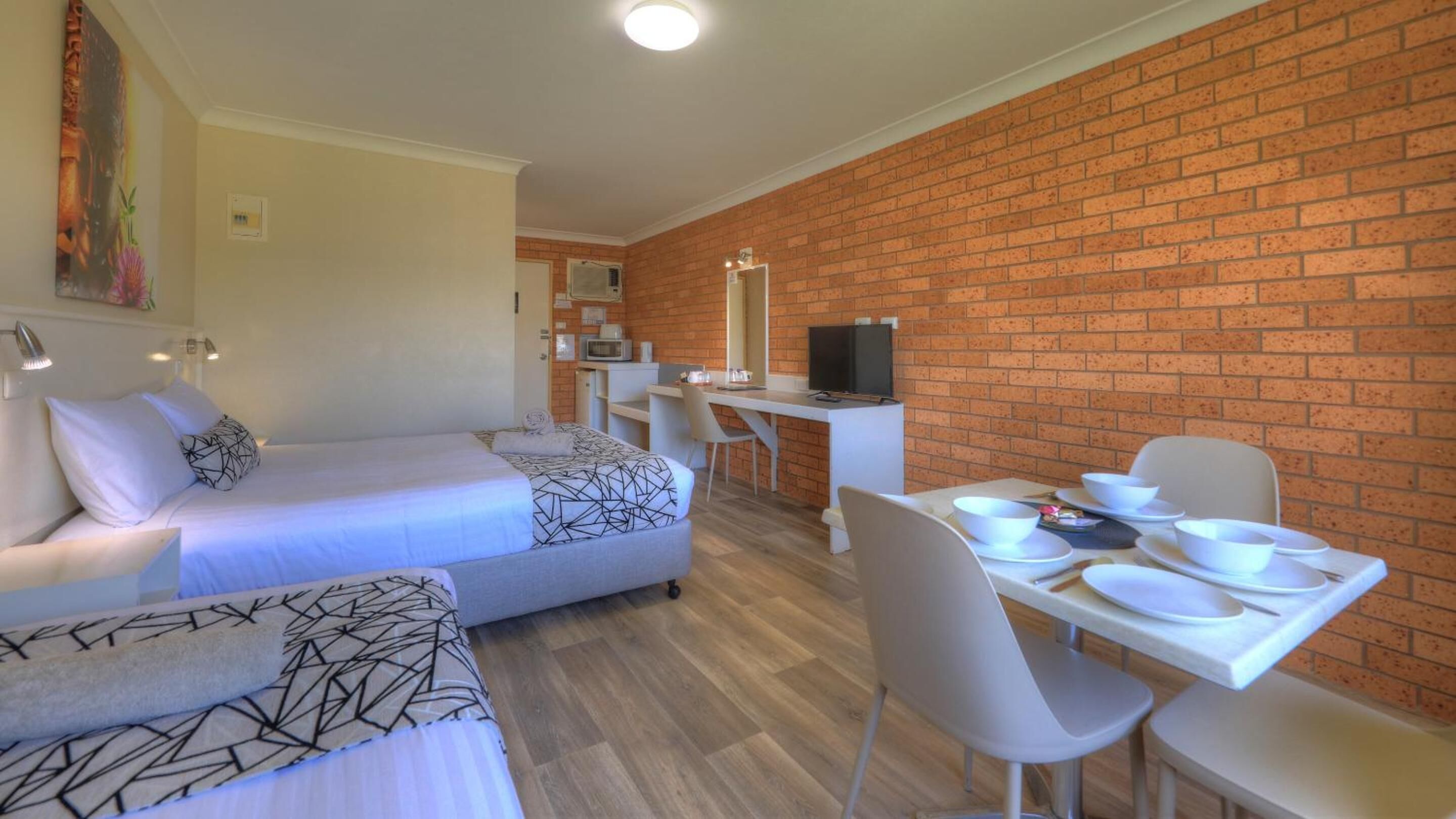 A hotel room with a bed, a desk, and a dining area.