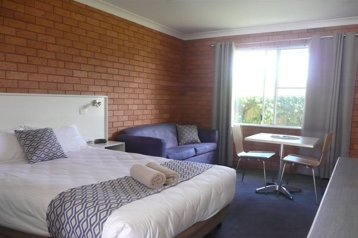 Ein Hotelzimmer mit einem großen Bett, einer kleinen Couch, einem Schreibtisch und einem Sessel.