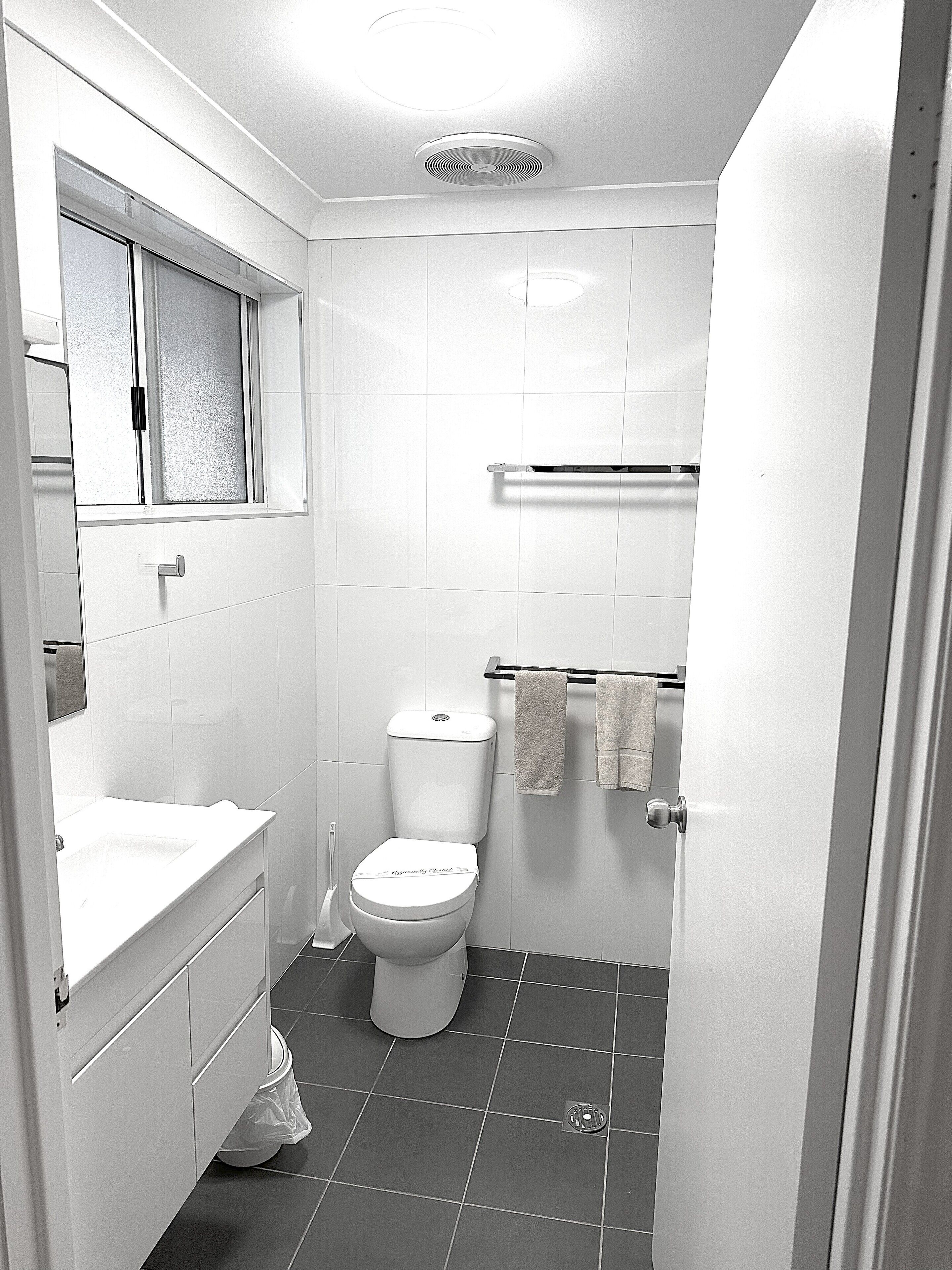 A small, modern bathroom with a toilet, sink, and mirror.