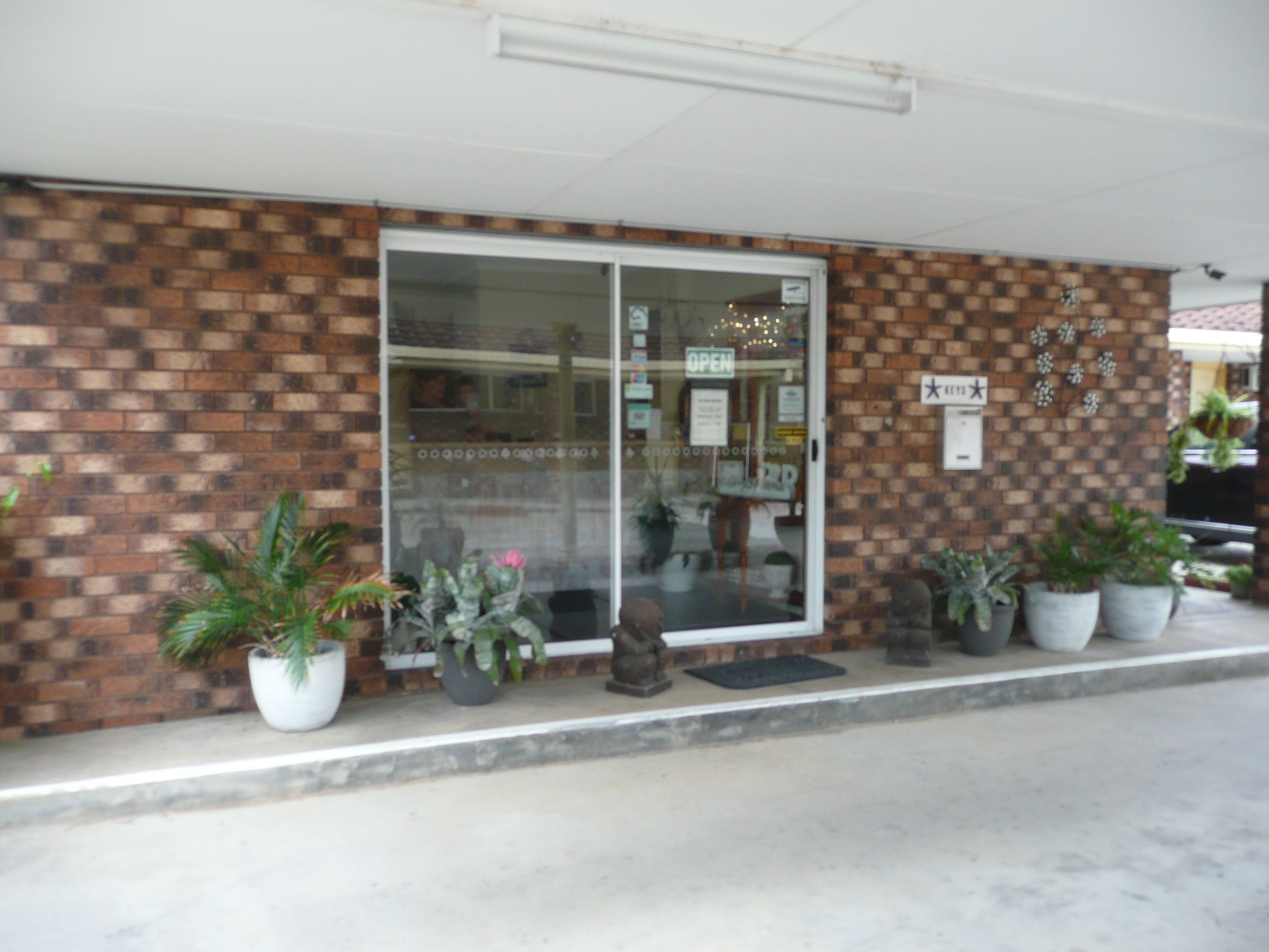 A storefront with a brick facade, a glass door, and several potted plants.