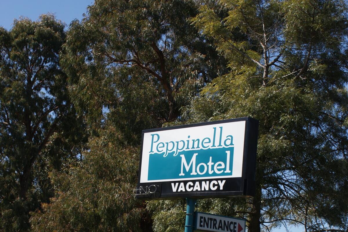 Schild für das Pepinella Motel mit Zimmerangebote und Wegweiser zum Eingang.