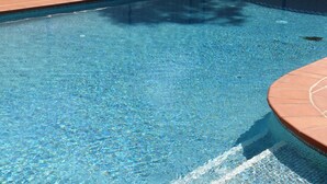 A clear swimming pool with a tiled edge and a wooden deck surrounding it. - Peppinella Motel (Delacombe)