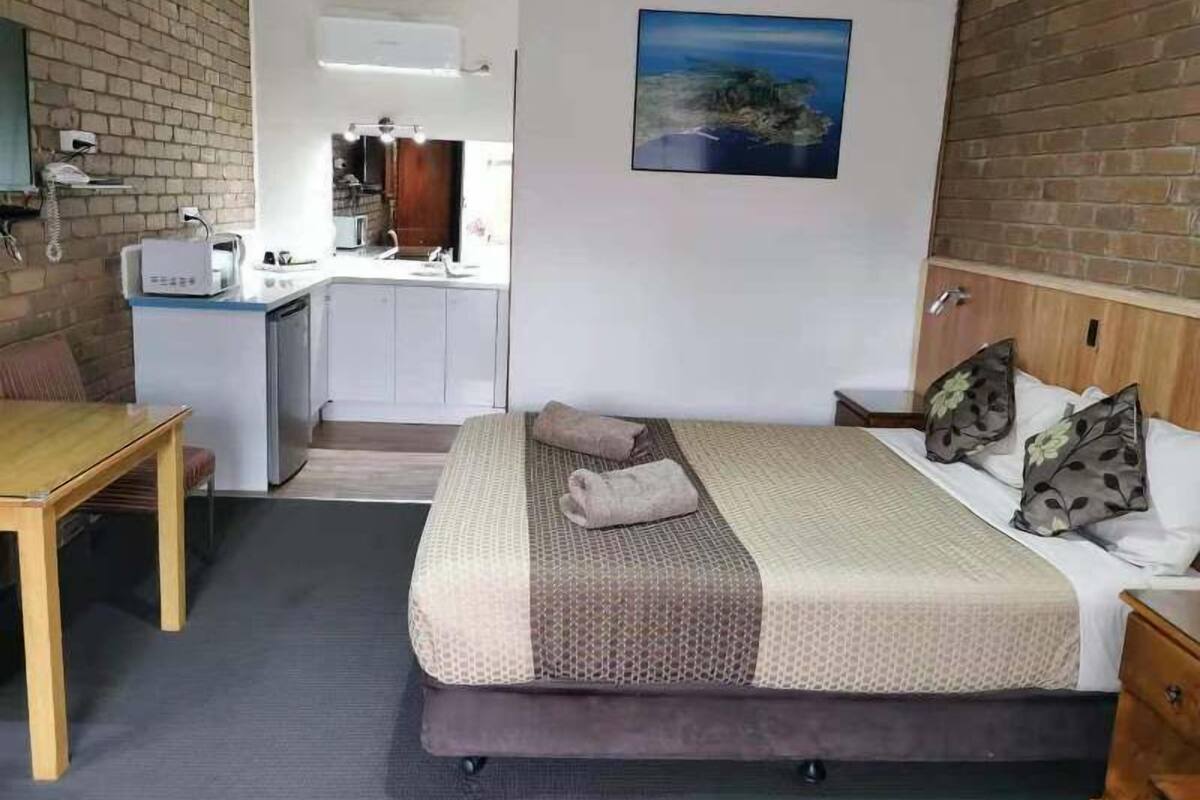 Ein Hotelzimmer mit Bett, Schreibtisch und einer Küchenzeile.