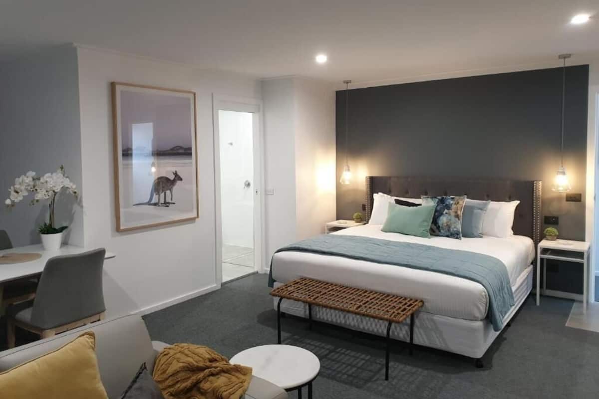 A modern hotel room with a large bed, bedside tables, a desk, and a chair.