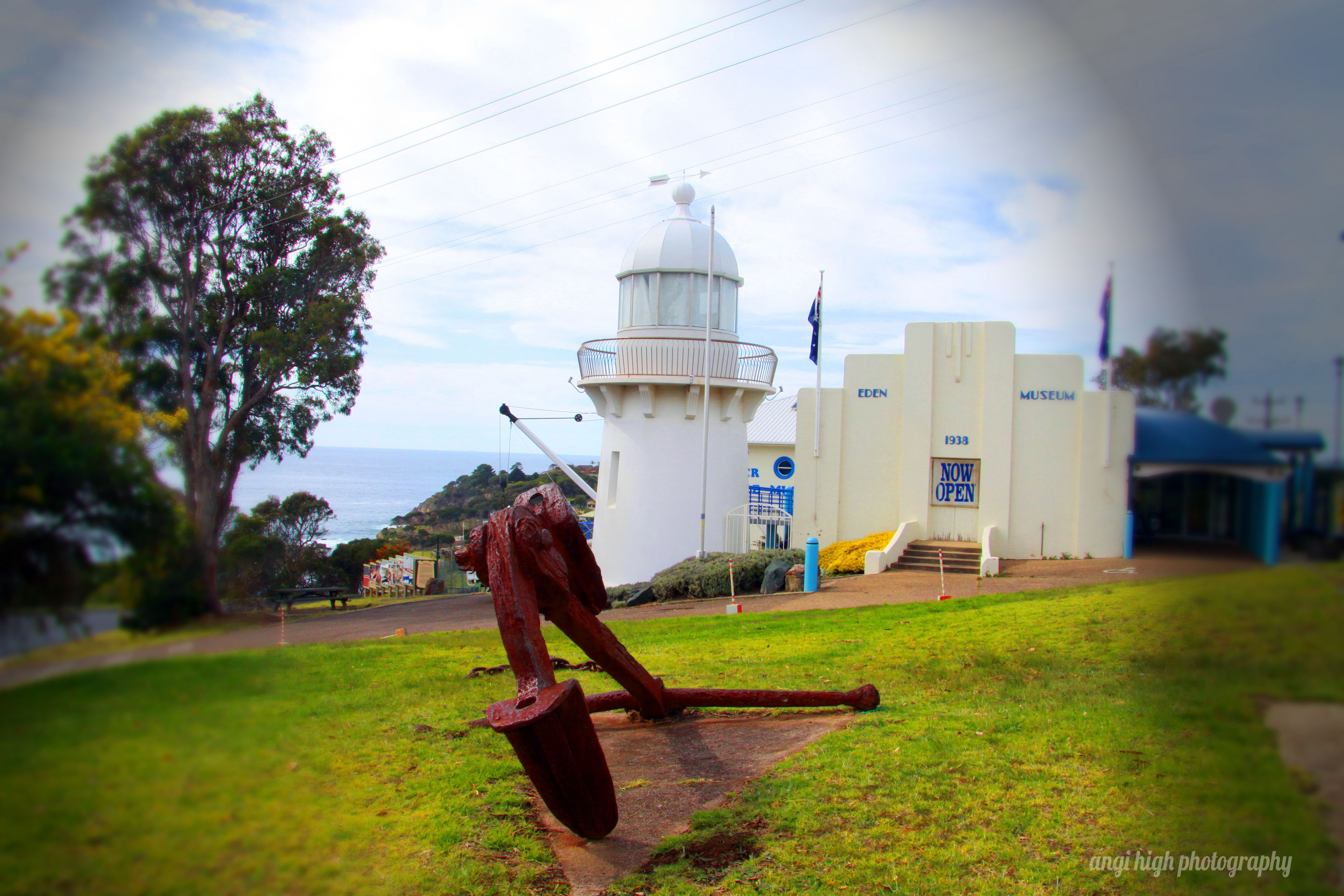 A lighthouse, a museum, and a grassy area with a large metal sculpture.