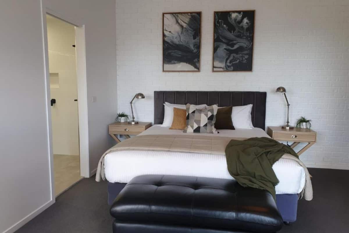 A modern bedroom with a large bed, two bedside tables, and artwork on the wall.