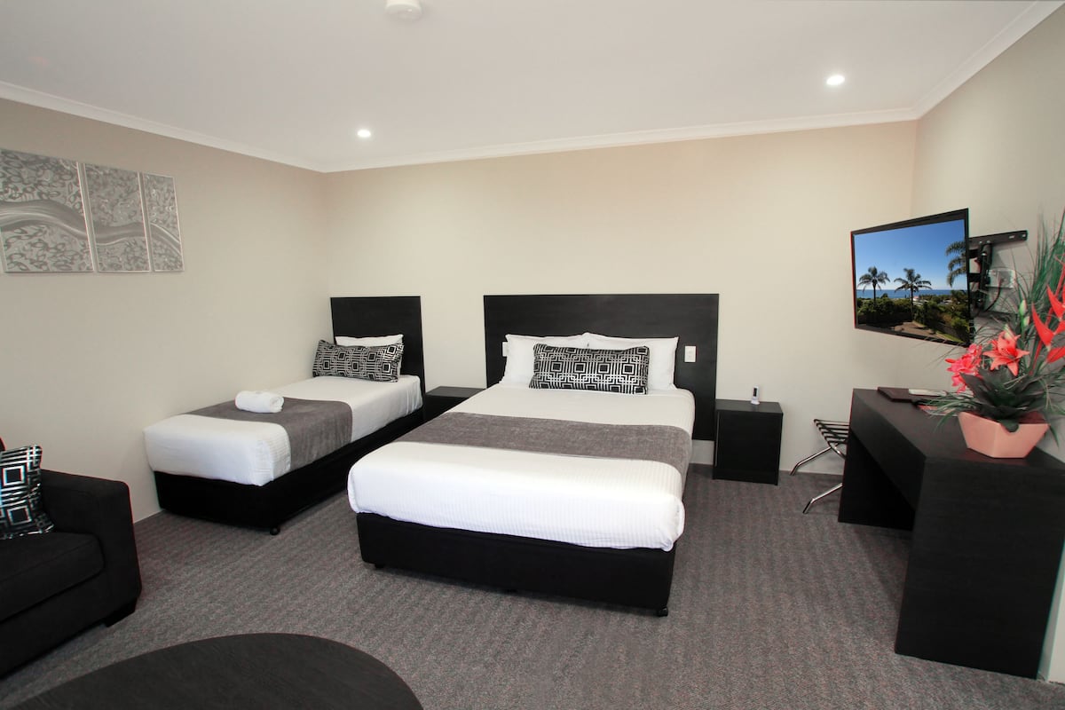 A hotel room with two beds, a desk, a chair, and a TV on the wall.
