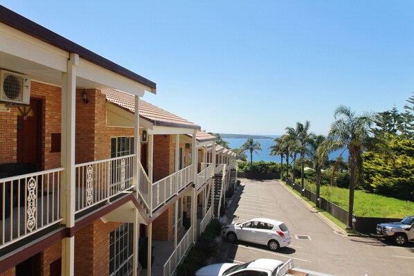 A multi-story hotel with a brick facade, balconies, and a parking lot.