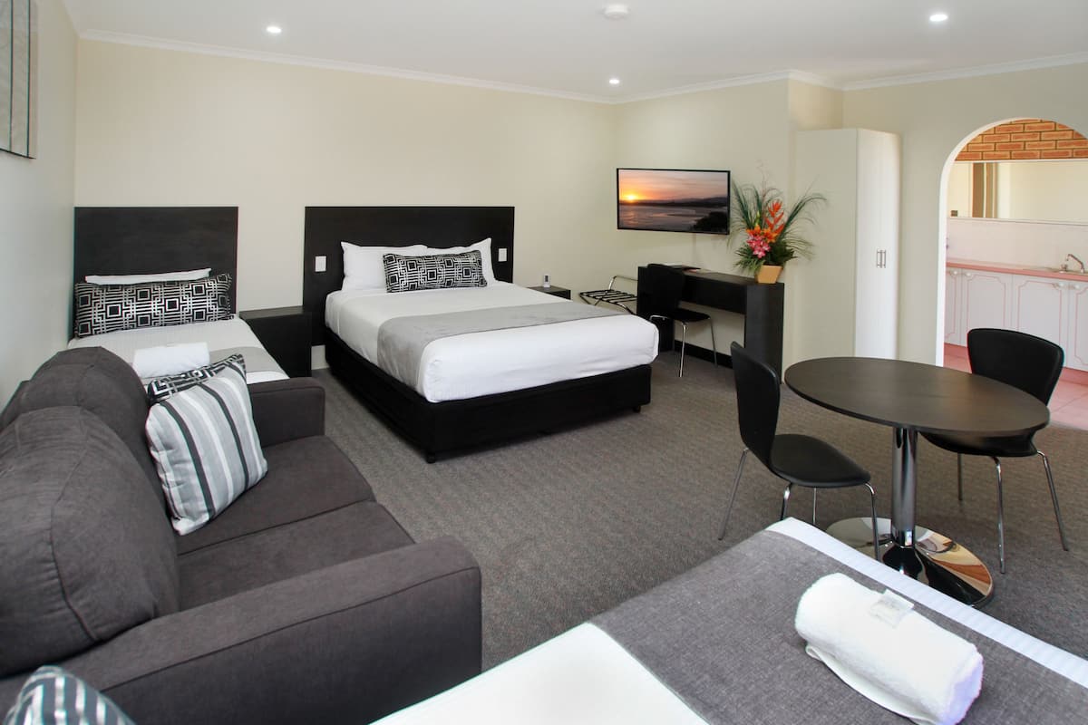 A hotel room with a bed, a sofa, a desk, a chair, and a small table.