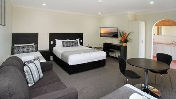 A hotel room with a bed, a sofa, a desk, a chair, and a small table.