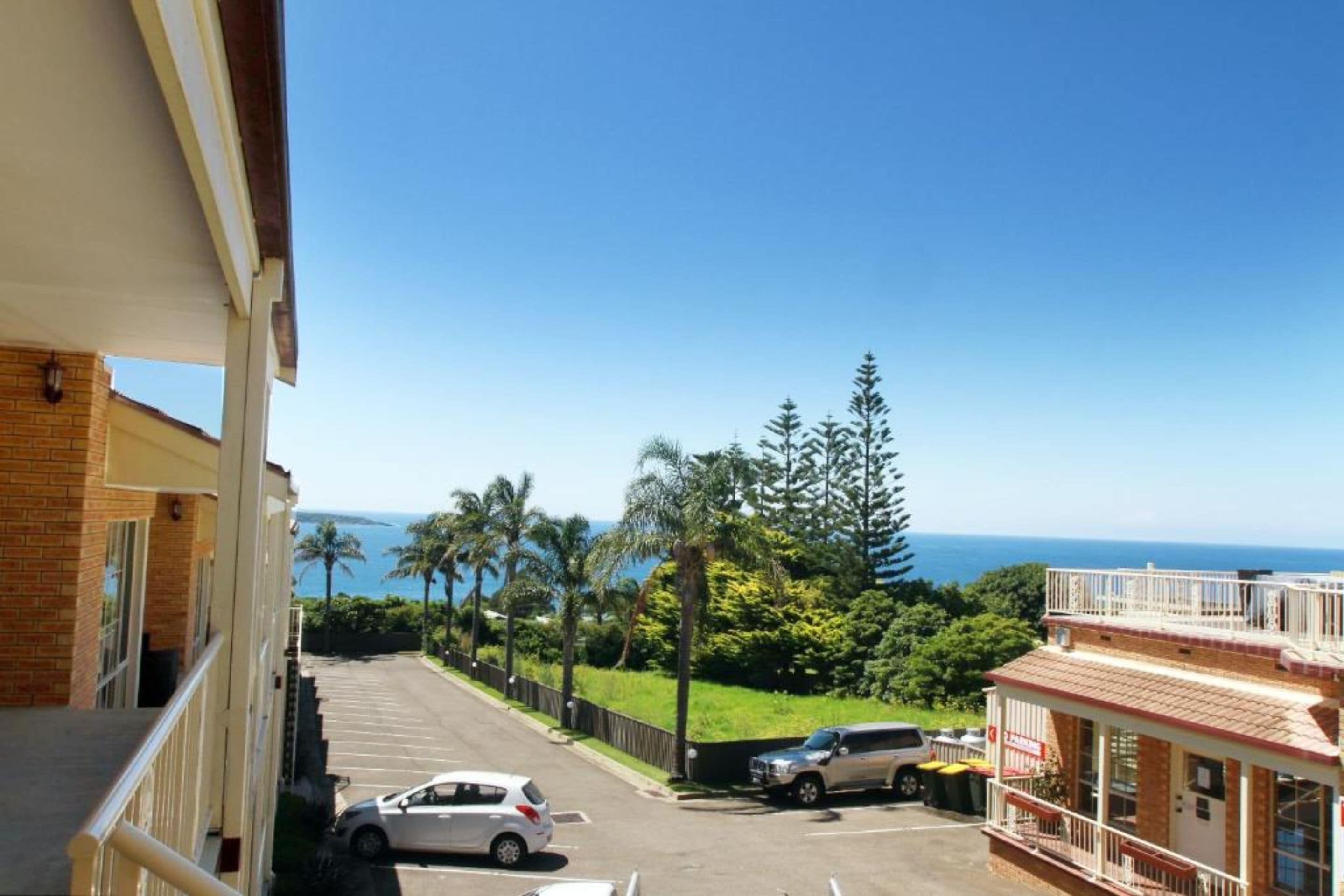 A parking lot with a view of the ocean and palm trees.