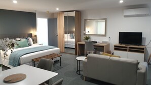 Una habitación de hotel moderna con cama, escritorio, televisor y zona de estar.