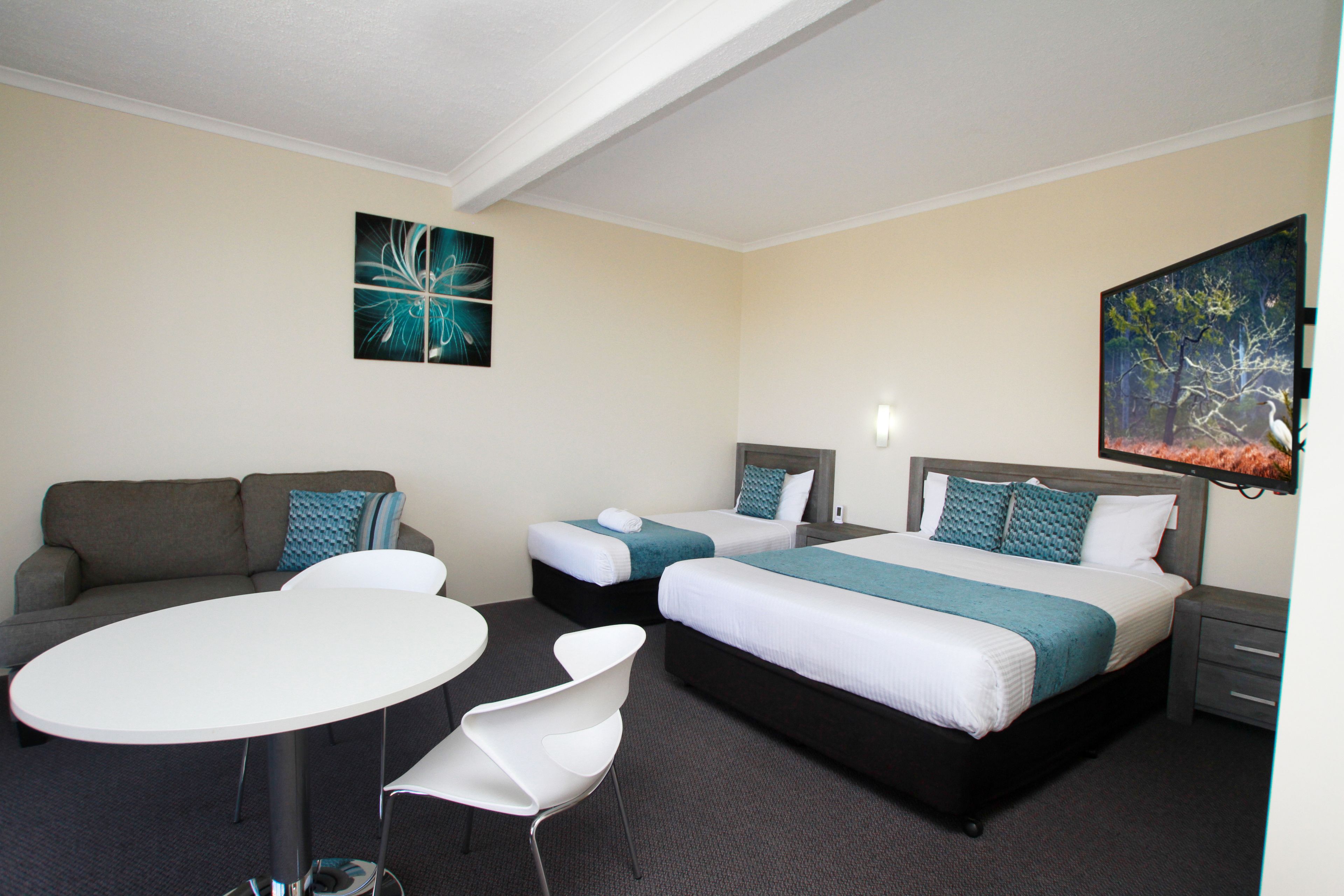 A hotel room with two beds, a sofa, a round table, and a chair.