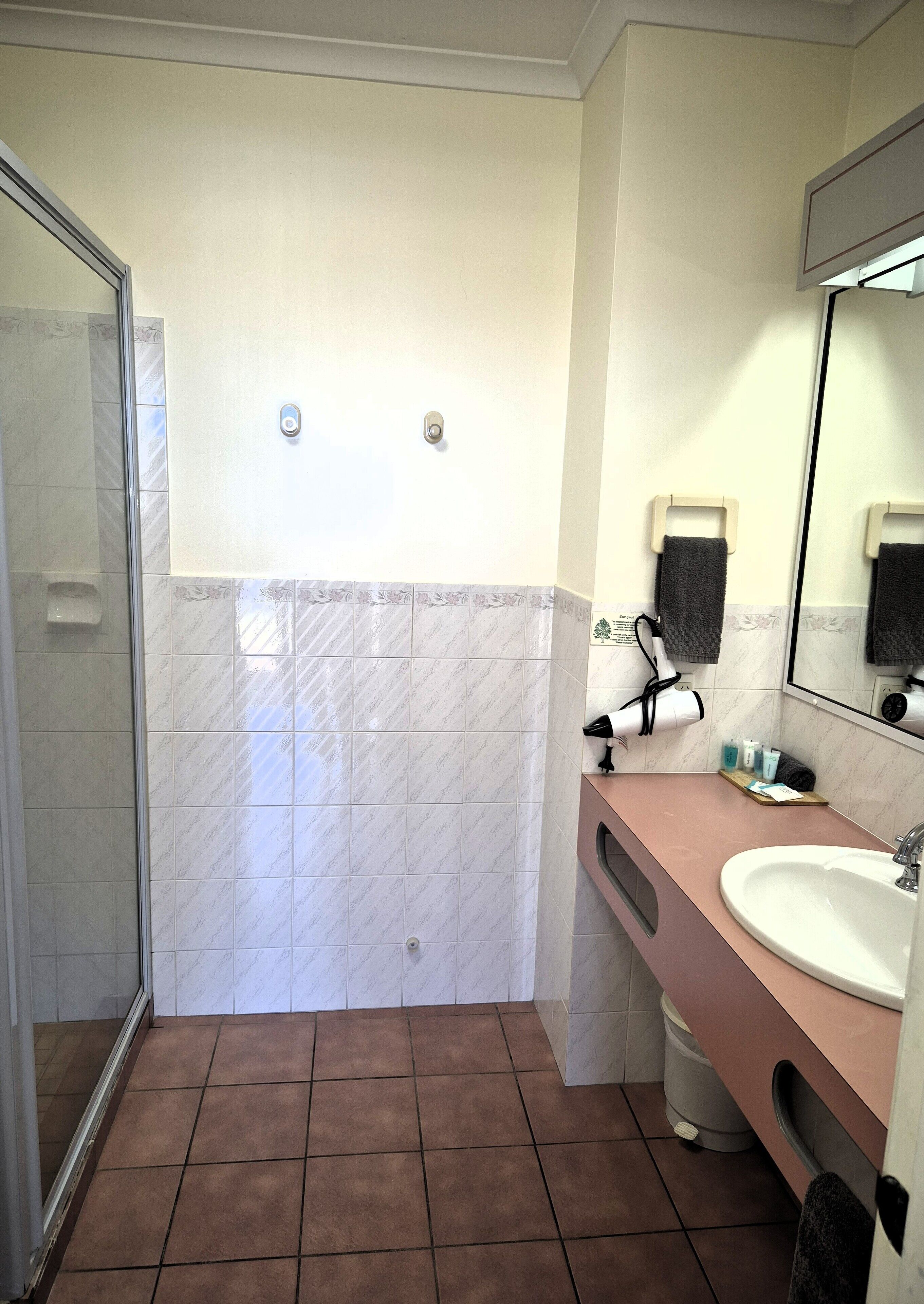 Een badkamer met een douche, wastafel en spiegel.