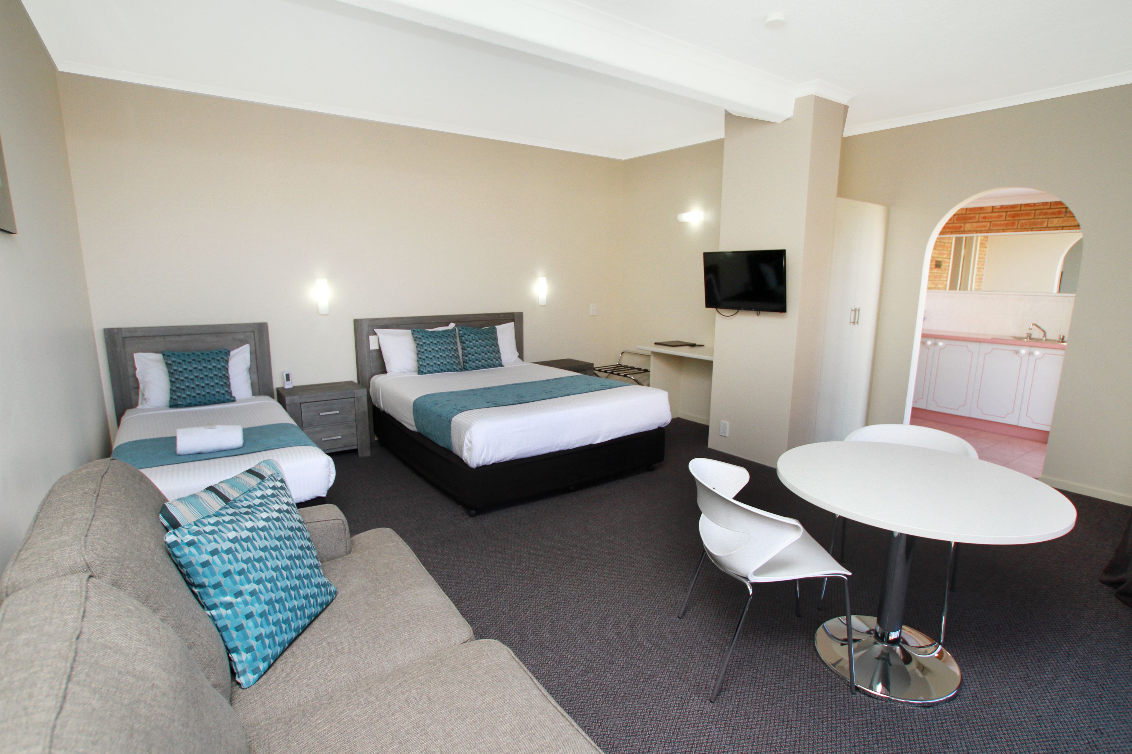 Habitación de hotel con dos camas, un sofá, una mesa de comedor y un televisor.