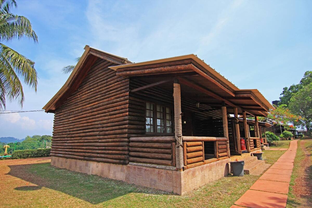 A log cabin with a porch and a small attached structure.