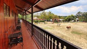 A covered outdoor area with wooden benches and a view of an equestrian arena. - Eagle Ranch Resort (Port Dickson)