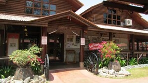 A wooden building with a porch, a sign reading "Eagle Ranch Resort," and a vintage wagon. - Eagle Ranch Resort (Port Dickson)