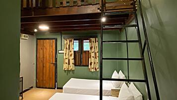 A dormitory room with bunk beds, a wooden ladder, a door, and a window with curtains.