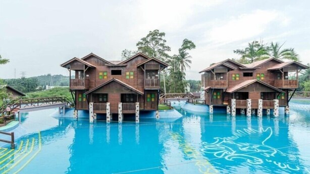 Two wooden buildings with balconies over a swimming pool. - Eagle Ranch Resort (Port Dickson)