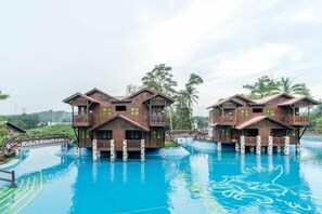 Two wooden buildings with balconies over a swimming pool. - Eagle Ranch Resort (Port Dickson)