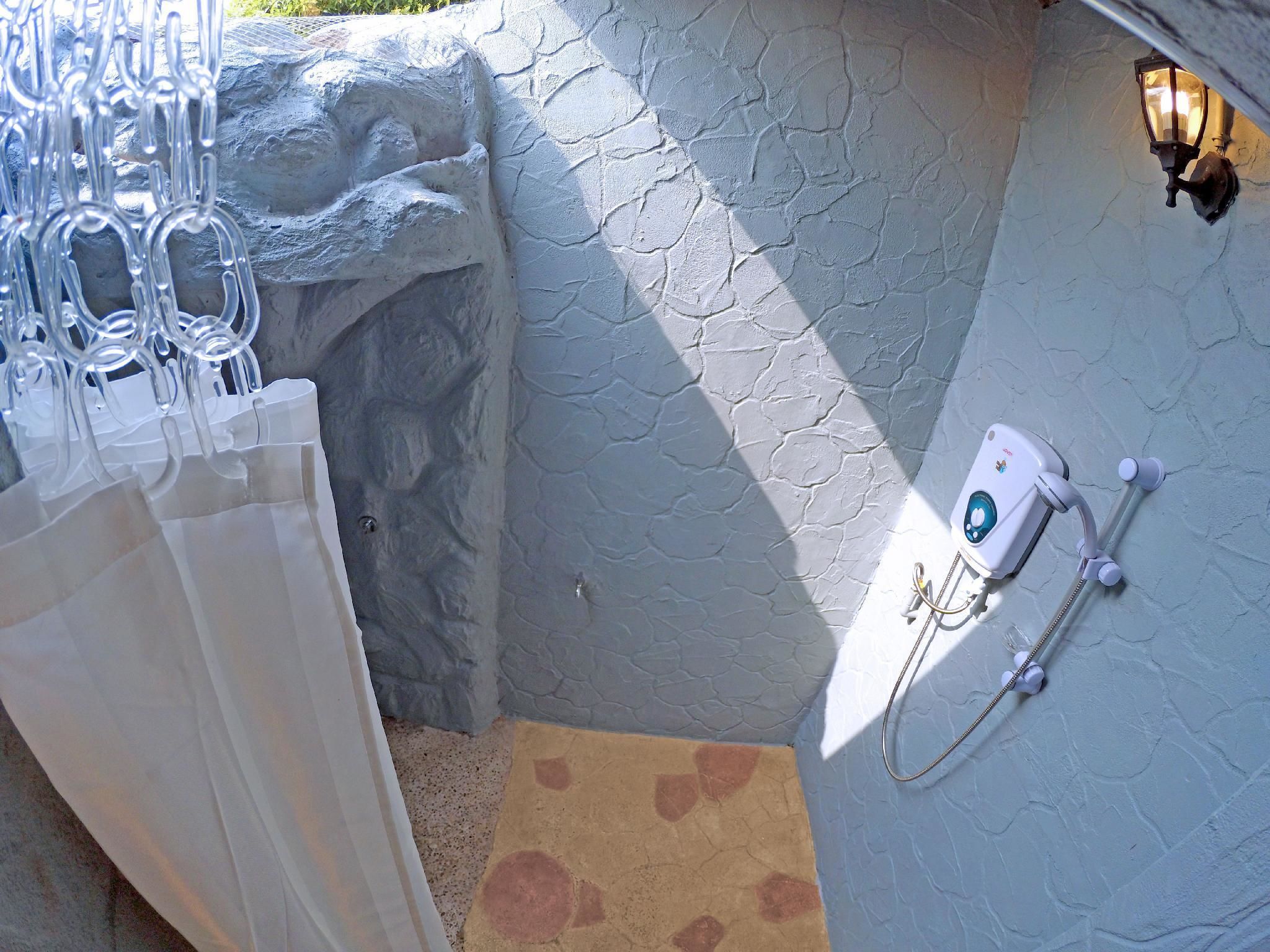 A bathroom with a stone wall, a shower head, and a towel rack.