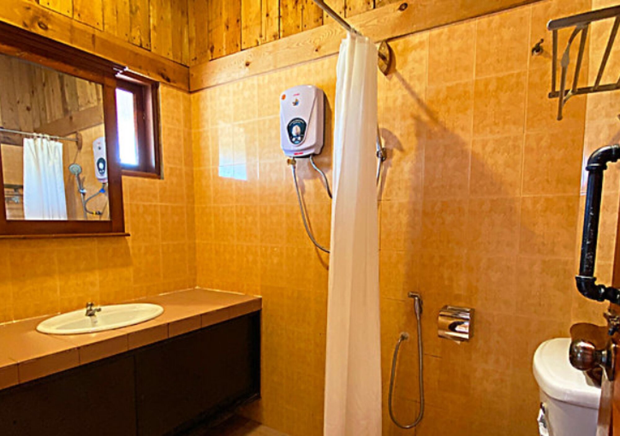 A bathroom with a wooden interior, a white sink, a shower with a control panel, and a toilet.