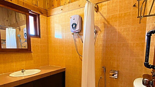 A bathroom with a wooden interior, a white sink, a shower with a control panel, and a toilet. - Eagle Ranch Resort (Port Dickson)
