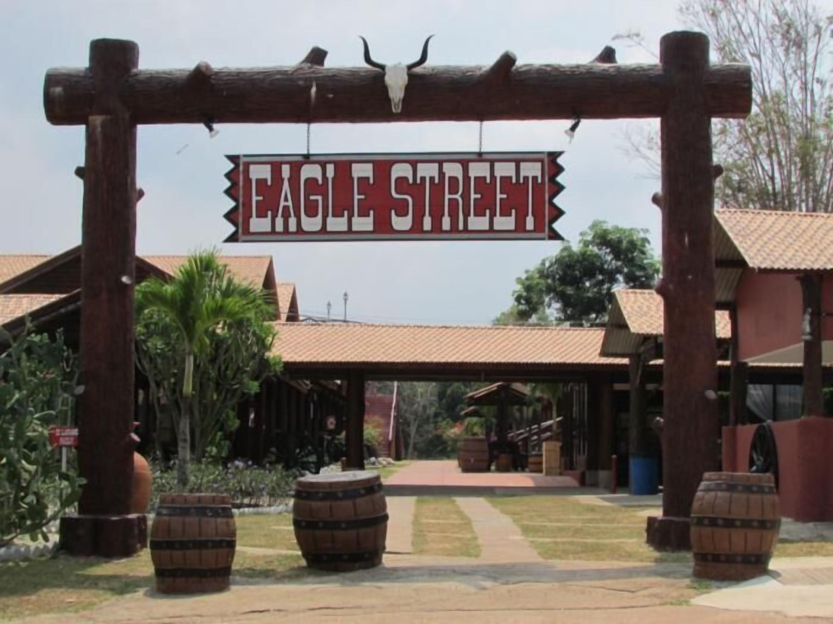 A wooden archway with the sign "EAGLE STREET" and a building with a tiled roof and wooden beams.