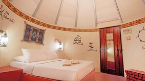 A room with a bed, a wooden door, and a wall with decorative elements. - Eagle Ranch Resort (Port Dickson)