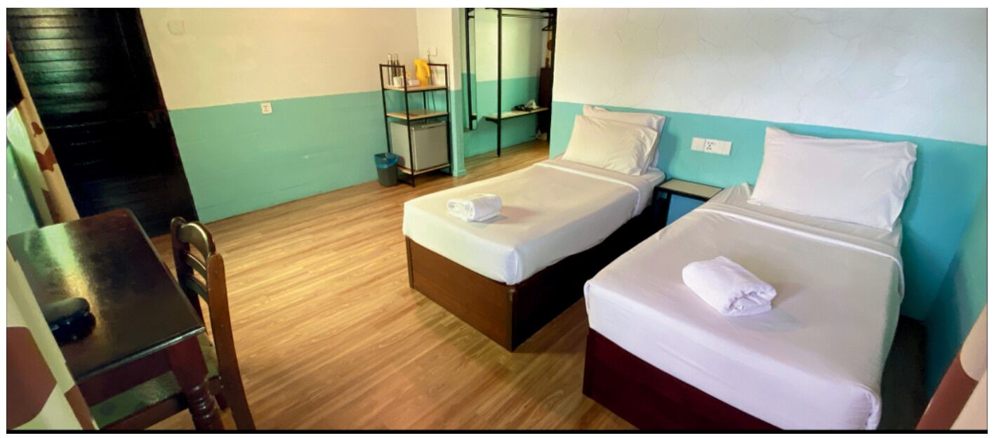 Habitación de hotel con dos camas, un escritorio y una silla.