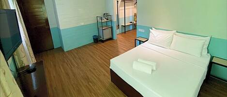 A hotel room with a bed, a small table, a shelf with toiletries, and a television.