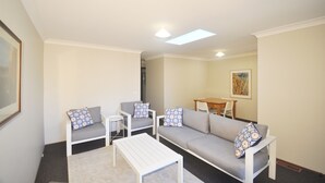 A modern living room with a sofa, two armchairs, a coffee table, and a dining table. - Katoomba Townhouses (Katoomba)